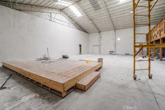 misc room with a towering ceiling and concrete flooring