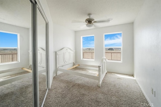 unfurnished bedroom featuring a textured ceiling, carpet, and ceiling fan