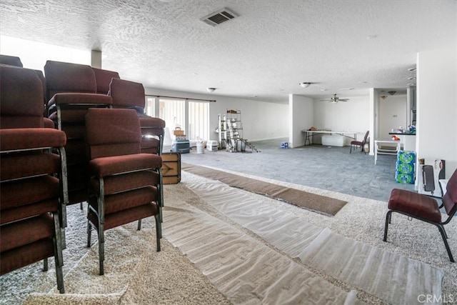 interior space featuring ceiling fan, a textured ceiling, and light carpet