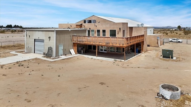 rear view of property with a wooden deck, a garage, and a patio area