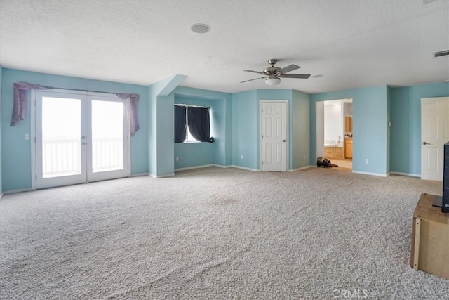 unfurnished living room featuring a textured ceiling, french doors, ceiling fan, and carpet floors