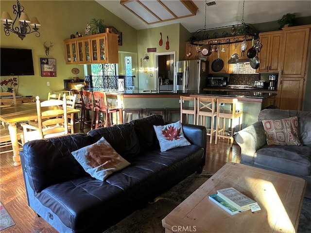living room featuring vaulted ceiling, wood finished floors, and an inviting chandelier