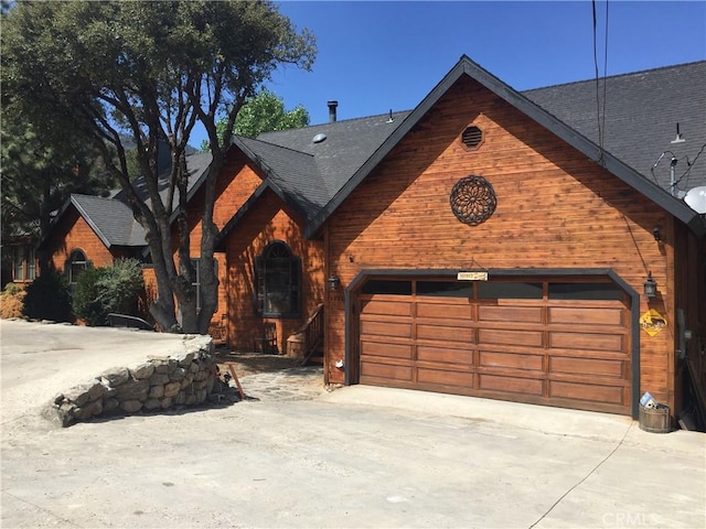 view of front facade with an attached garage, roof with shingles, and driveway