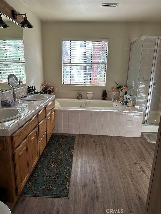 bathroom featuring a shower stall, wood finished floors, and a healthy amount of sunlight