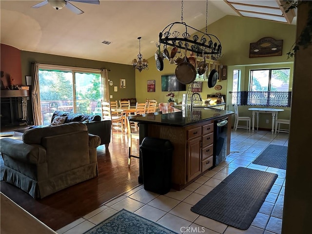 kitchen featuring light tile patterned flooring, dark countertops, a wealth of natural light, and ceiling fan with notable chandelier
