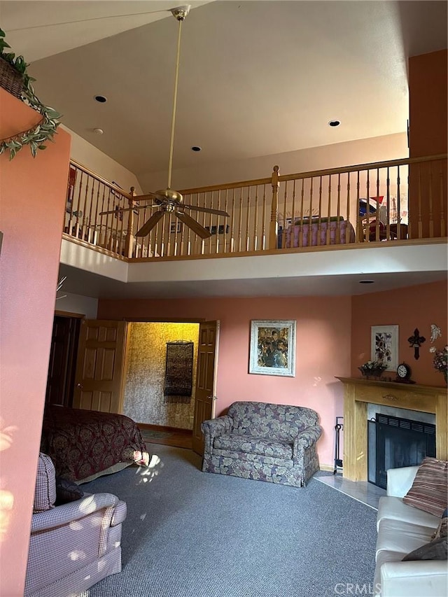 carpeted living room featuring a fireplace, a towering ceiling, a ceiling fan, and recessed lighting