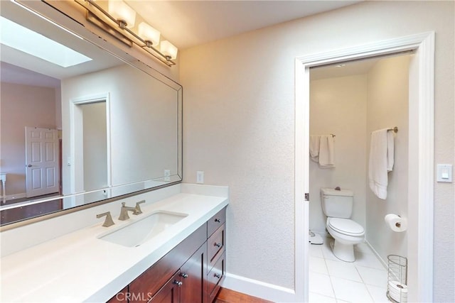 bathroom with tile patterned flooring, vanity, a skylight, and toilet