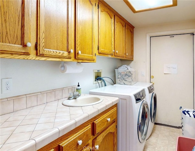 laundry room with washing machine and dryer, cabinets, and sink