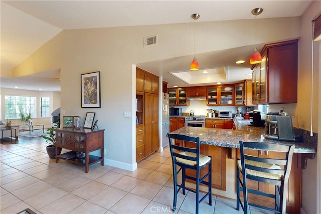 kitchen featuring light tile patterned flooring, lofted ceiling, kitchen peninsula, and decorative light fixtures