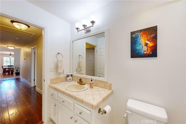 bathroom with toilet, vanity, and wood-type flooring