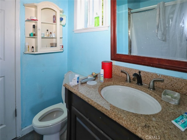 bathroom featuring a shower with door, vanity, and toilet