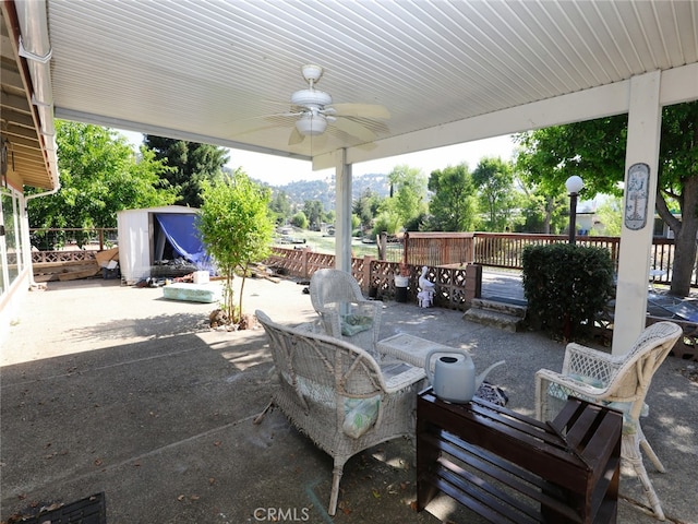 view of patio / terrace featuring a wooden deck, ceiling fan, and a storage shed