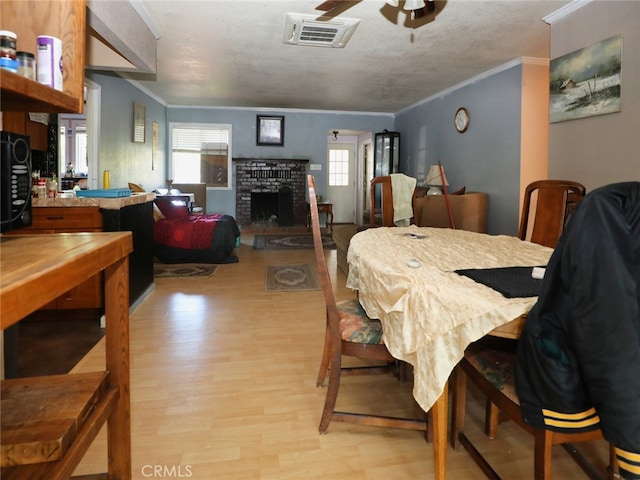 dining area featuring plenty of natural light, ceiling fan, light wood-type flooring, and a brick fireplace