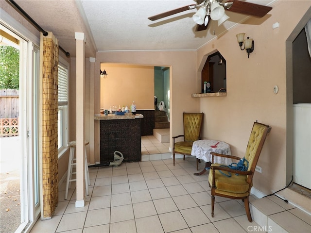 sitting room featuring ceiling fan, light tile patterned floors, and a textured ceiling