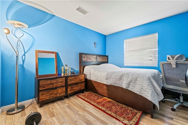 bedroom with visible vents, baseboards, and wood finished floors