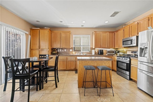 kitchen featuring light tile patterned floors, visible vents, a kitchen island, and appliances with stainless steel finishes