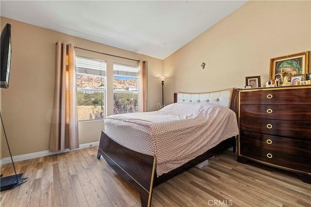 bedroom featuring baseboards, wood finished floors, and vaulted ceiling