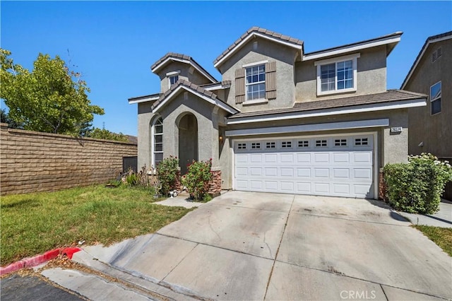 traditional-style house featuring concrete driveway, a garage, and stucco siding