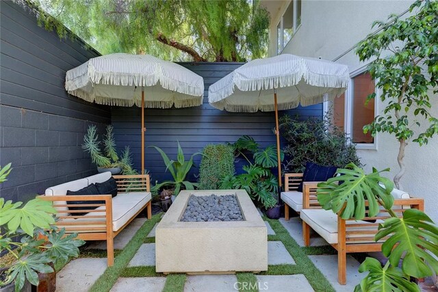 view of patio with an outdoor living space with a fire pit