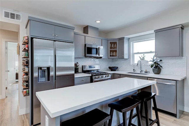 2151 S W View St, Los Angeles, CA 90016 - kitchen featuring appliances with stainless steel finishes, gray cabinetry, backsplash, a breakfast bar area, and recessed lighting