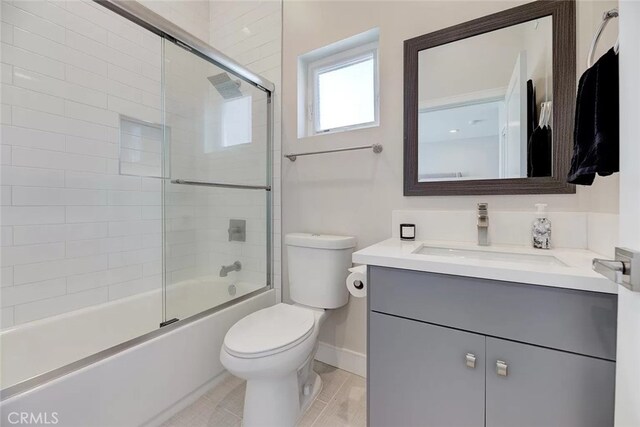 full bathroom with tile patterned flooring, toilet, bath / shower combo with glass door, and vanity