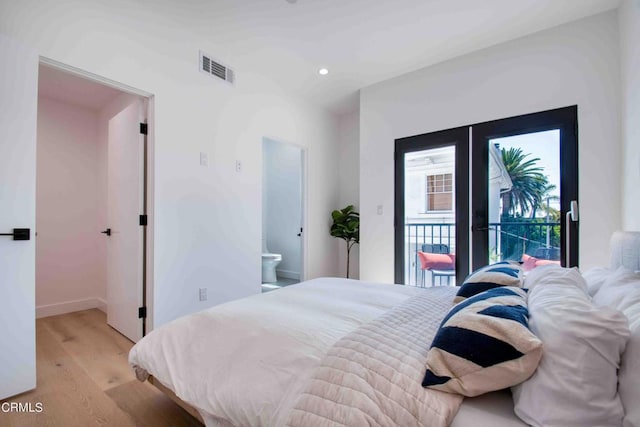 bedroom with ensuite bathroom, access to exterior, and light hardwood / wood-style floors