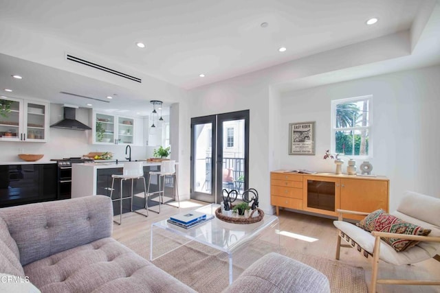 living room featuring light hardwood / wood-style flooring, french doors, and sink