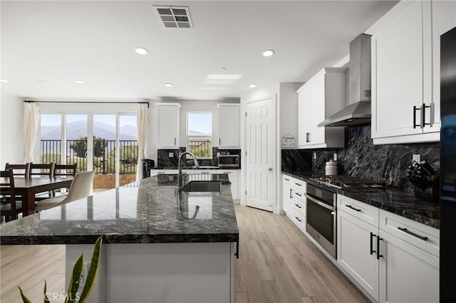 kitchen featuring a center island with sink, a mountain view, white cabinetry, and appliances with stainless steel finishes