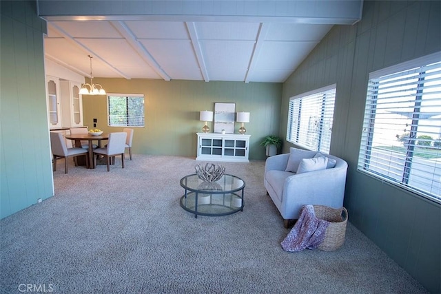 carpeted living room with a notable chandelier and lofted ceiling