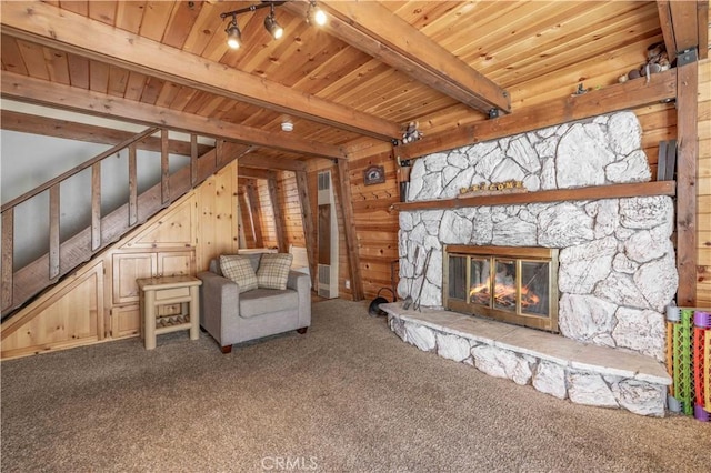 unfurnished room featuring carpet, beam ceiling, a stone fireplace, and wooden ceiling