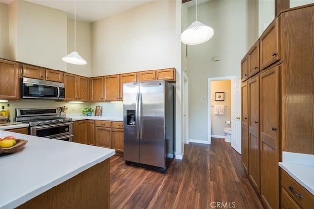 kitchen featuring a towering ceiling, stainless steel appliances, and hanging light fixtures