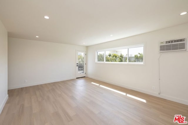 empty room with light wood-type flooring and a wall mounted air conditioner