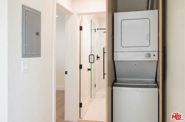 clothes washing area featuring light hardwood / wood-style flooring, stacked washer / drying machine, and electric panel