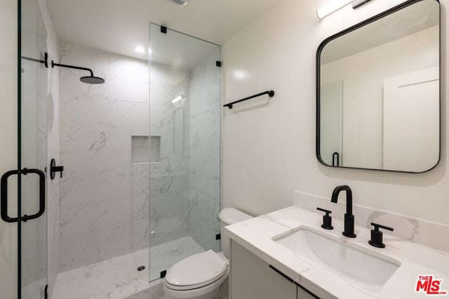 bathroom featuring vanity, a shower with door, and toilet