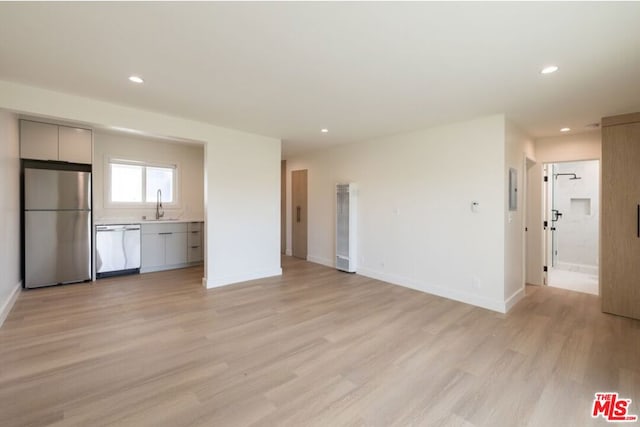 unfurnished living room featuring sink and light hardwood / wood-style floors