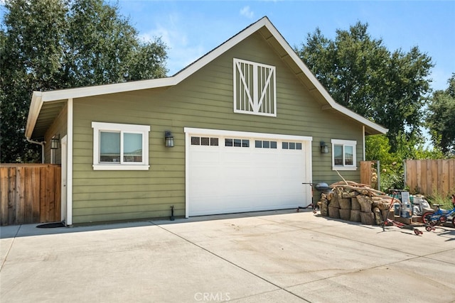 garage featuring fence and concrete driveway