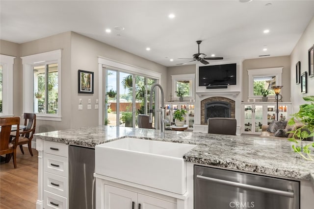 kitchen featuring open floor plan, a sink, light wood finished floors, ceiling fan, and dishwasher