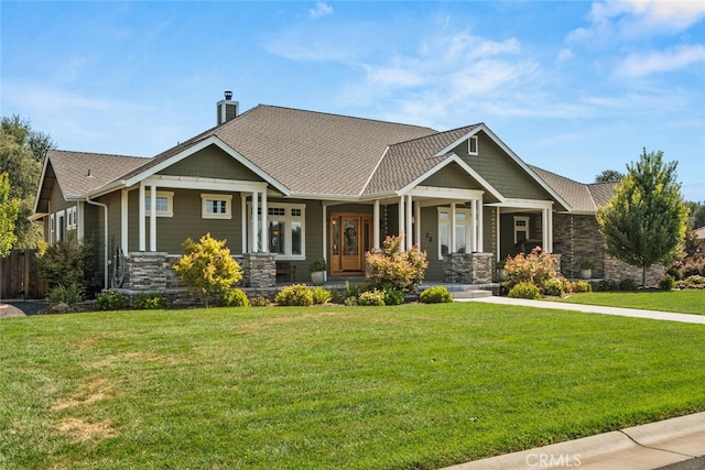 craftsman house with stone siding, a chimney, fence, and a front yard
