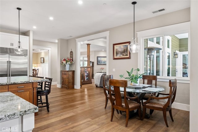 dining space featuring decorative columns and light hardwood / wood-style flooring