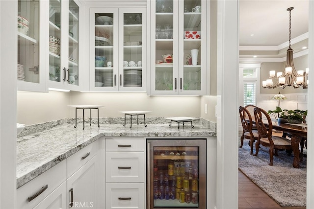bar featuring a chandelier, crown molding, wood finished floors, beverage cooler, and pendant lighting