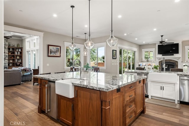 kitchen featuring light hardwood / wood-style flooring, ceiling fan, white cabinets, stainless steel dishwasher, and an island with sink