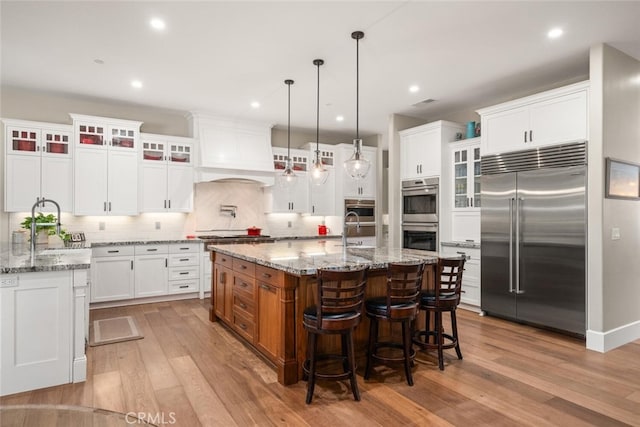 kitchen featuring backsplash, a center island with sink, stainless steel appliances, and light hardwood / wood-style floors