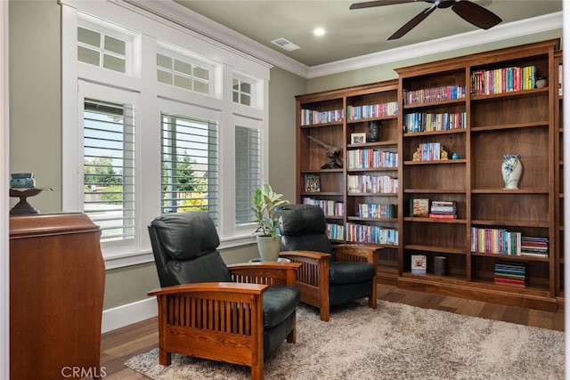 living area featuring visible vents, baseboards, ornamental molding, wood finished floors, and a ceiling fan