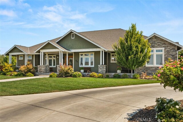 craftsman house with stone siding, a front yard, and french doors