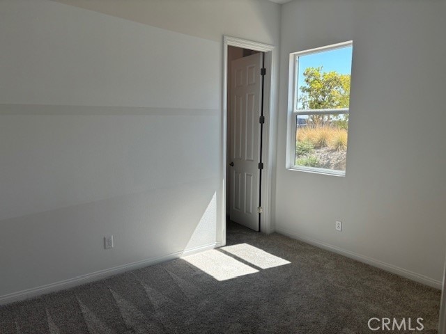 empty room featuring dark carpet and a wealth of natural light