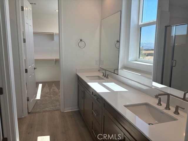 bathroom featuring dual vanity, hardwood / wood-style floors, and a shower with shower door