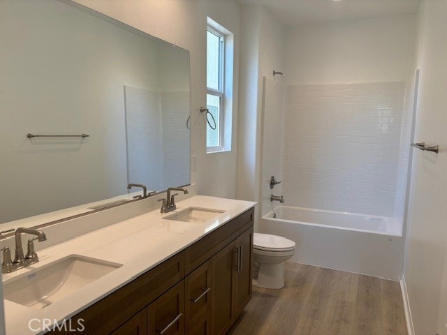 full bathroom with toilet, hardwood / wood-style flooring, dual vanity, and a healthy amount of sunlight