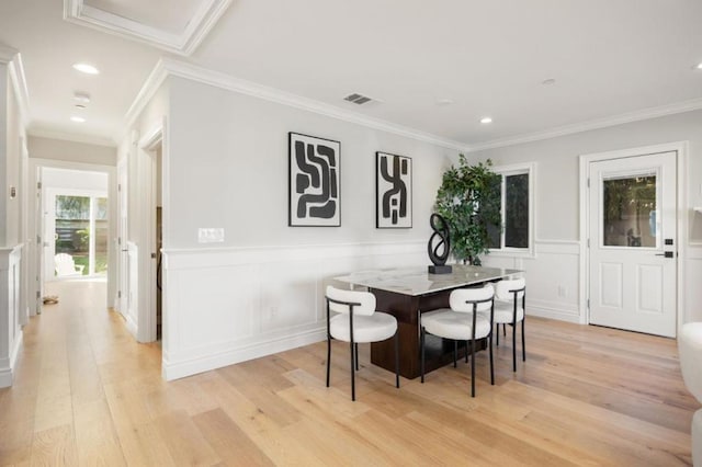 dining space with ornamental molding and light wood-type flooring