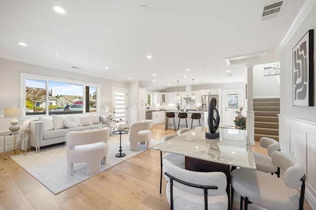 dining space featuring ornamental molding and light hardwood / wood-style flooring