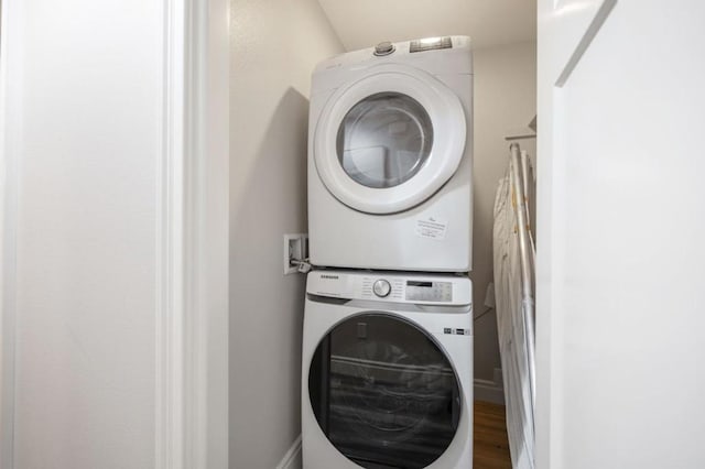 laundry room with hardwood / wood-style flooring and stacked washing maching and dryer